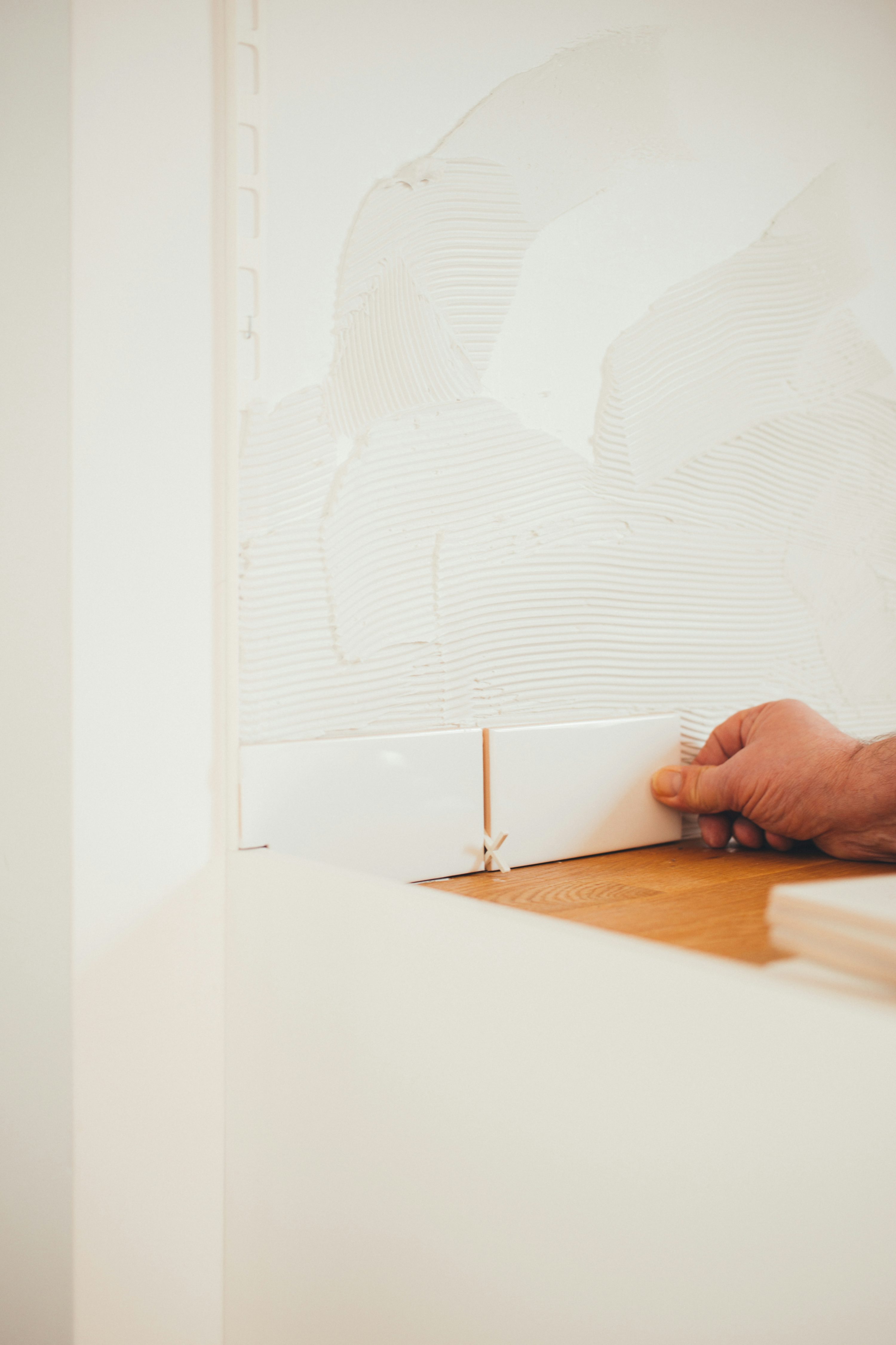 Professional hand setting wall tile with spacer and adhesive